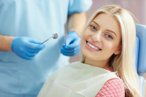 Woman Smiling While Getting Teeth Cleaning